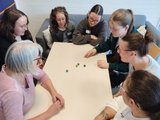 Gemeinsam spielen Das Bild zeigt fünf Schülerinnen und drei Lehrkräfte, die ein neues Spiel kennenlernen.