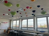 Buntes Klassenzimmer Das Bild zeigt die Decke des Unterkurs-Klassenzimmers, in dem bunte Halbkugeln von der Decke hängen. Sie erfüllen den Zweck der Schallabsorption