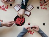 Spiele ausprobieren Das Bild zeigt die Hände von drei Schülerinnen, die sich Spielchips vom Spielbrett nehmen.