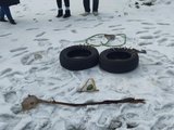 Das Bild zeigt eine Land-Art-Figur aus Stöcken, Blättern und im Wald gefundenem Müll im Schnee. Sie stellt einen Smiley dar.