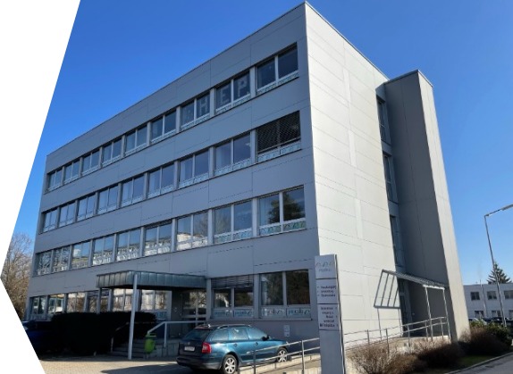 Das Foto zeigt das Schulgebäude von außen mitsamt dem bunten Schriftzug HEP in den Fenstern des dritten Stockwerks und einem schwarzen Chamäleon im Fenster rechts daneben.