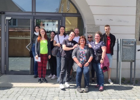 Die Schüler:innen der Heilerziehungspflegehilfe stehen vor dem Eingang der Regionalbibliothek Weiden zu einem Gruppenfoto nebeneinander.