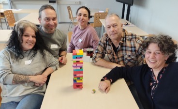 Das Foto zeigt fünf Schüler*innen der Heilerziehungspflegehilfe, die vor ihrem Jenga-Turm für ein Foto posieren.